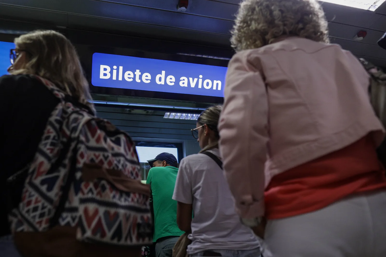 Pasageri așteptând la un ghișeu pentru bilete de avion.