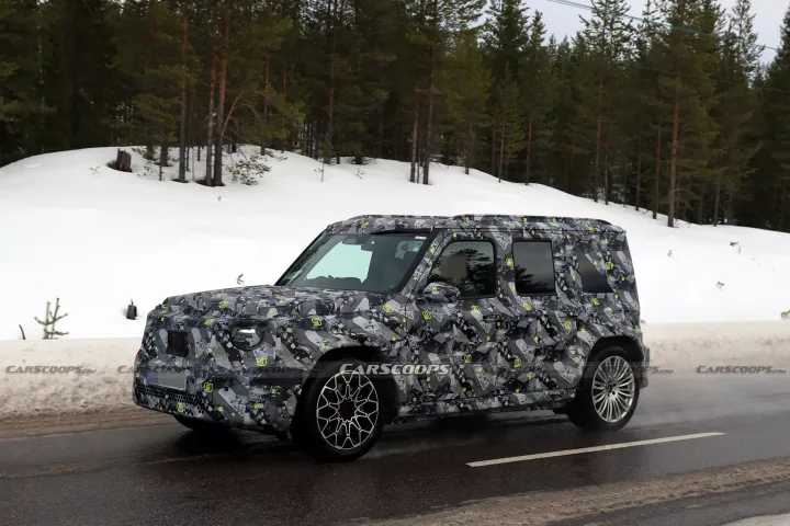 Un vehicul camuflat pe un drum de munte, înconjurat de zăpadă și copaci verzi.