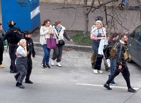 Civilii evacuându-se în urma unui atac armat în Kiev, cu polițiști în apropiere.