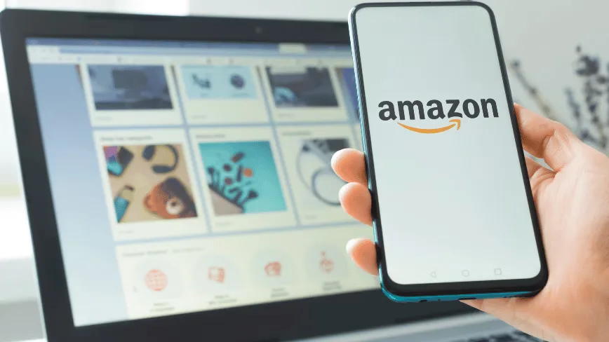 Un telefon mobil cu logo-ul Amazon lângă un laptop deschis.