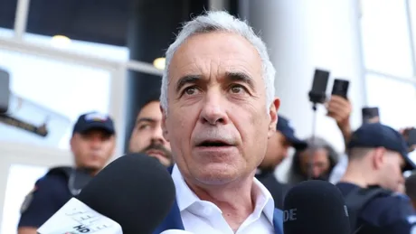 Călin Georgescu discută cu jurnaliști în fața unei clădiri, înconjurat de oameni.