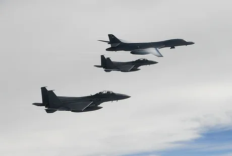Avioane militare zburând în formare pe un cer noros.