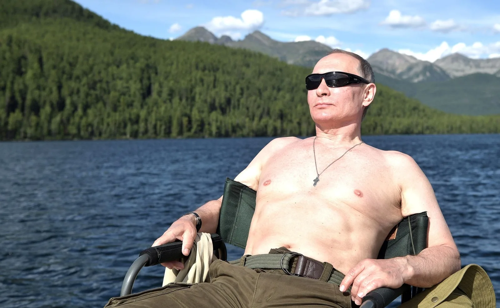 Un bărbat relaxându-se pe malul unei ape, înconjurat de natură.