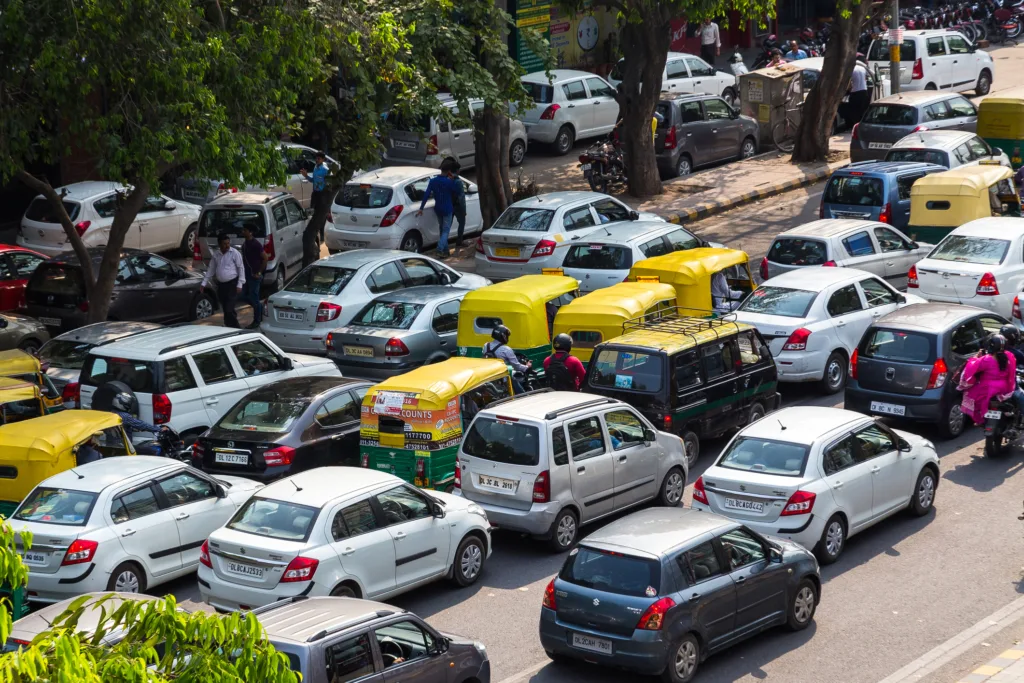Trafic aglomerat în oraș, cu mașini diverse parcate și circulând.