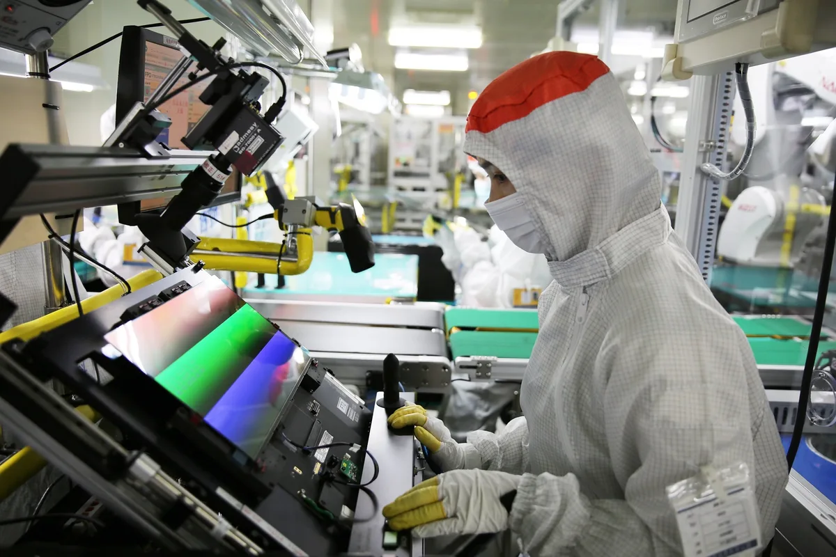 Angajat în fabrică, lucrând la panouri OLED pentru smartphone-uri.