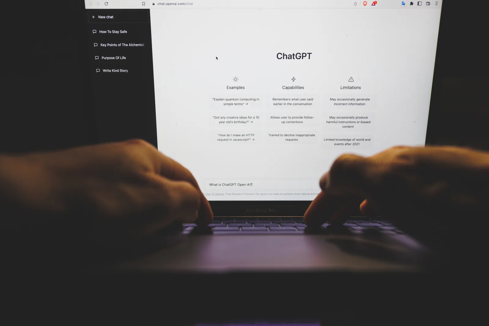 Ecran de laptop cu interfața ChatGPT deschisă, mâini pe tastatură.