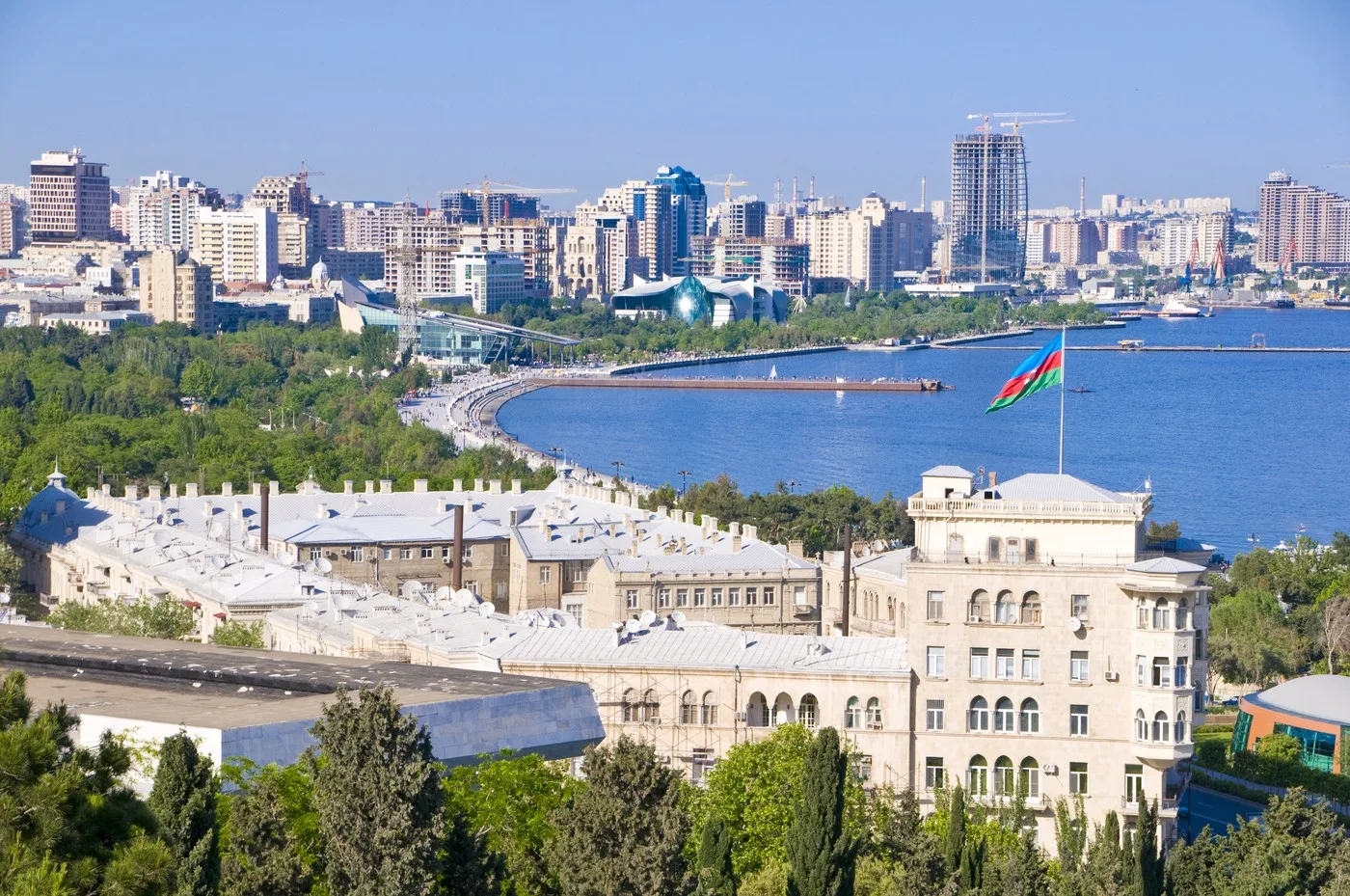 Peisaj urban din Baku, cu clădiri moderne și steagul Azerbaidjanului fluturând.