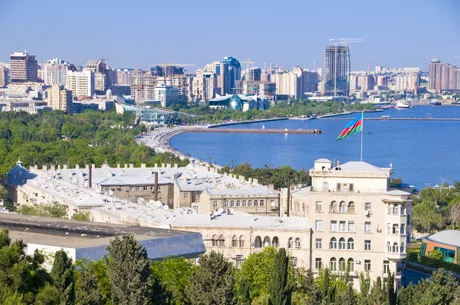 Peisaj urban din Baku, cu clădiri moderne și steagul Azerbaidjanului fluturând.