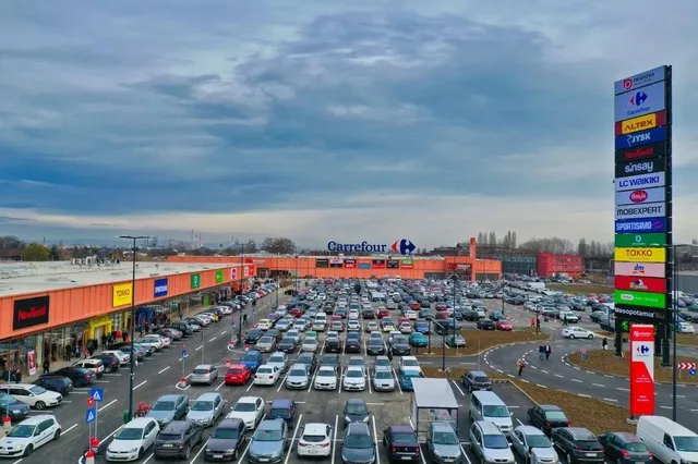 Centre comerciale open-air pline de mașini, cu un cer înnorat deasupra.