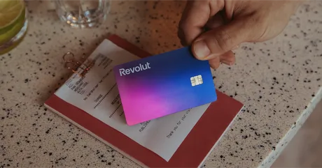 Card Revolut pe un fundal de notă de plată, simbolizând succesul financiar.
