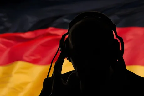 Silhouette de bărbat cu căști, pe fundalul steagului Germaniei.
