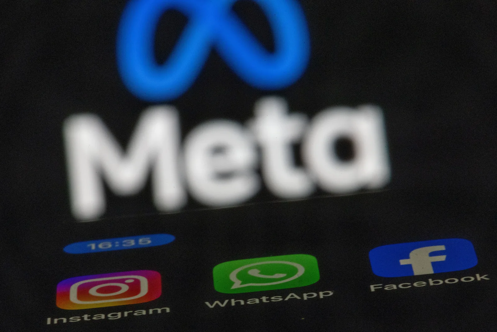 Logo-ul Meta pe un ecran, cu aplicațiile Instagram, WhatsApp și Facebook vizibile.