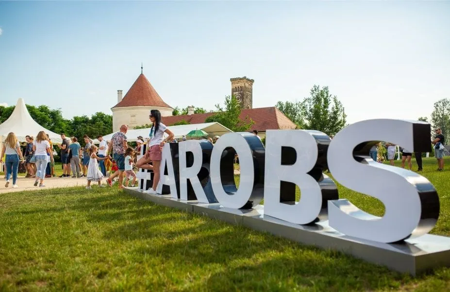 Eveniment AROBS cu participanți și activități în aer liber, într-un cadru festiv.