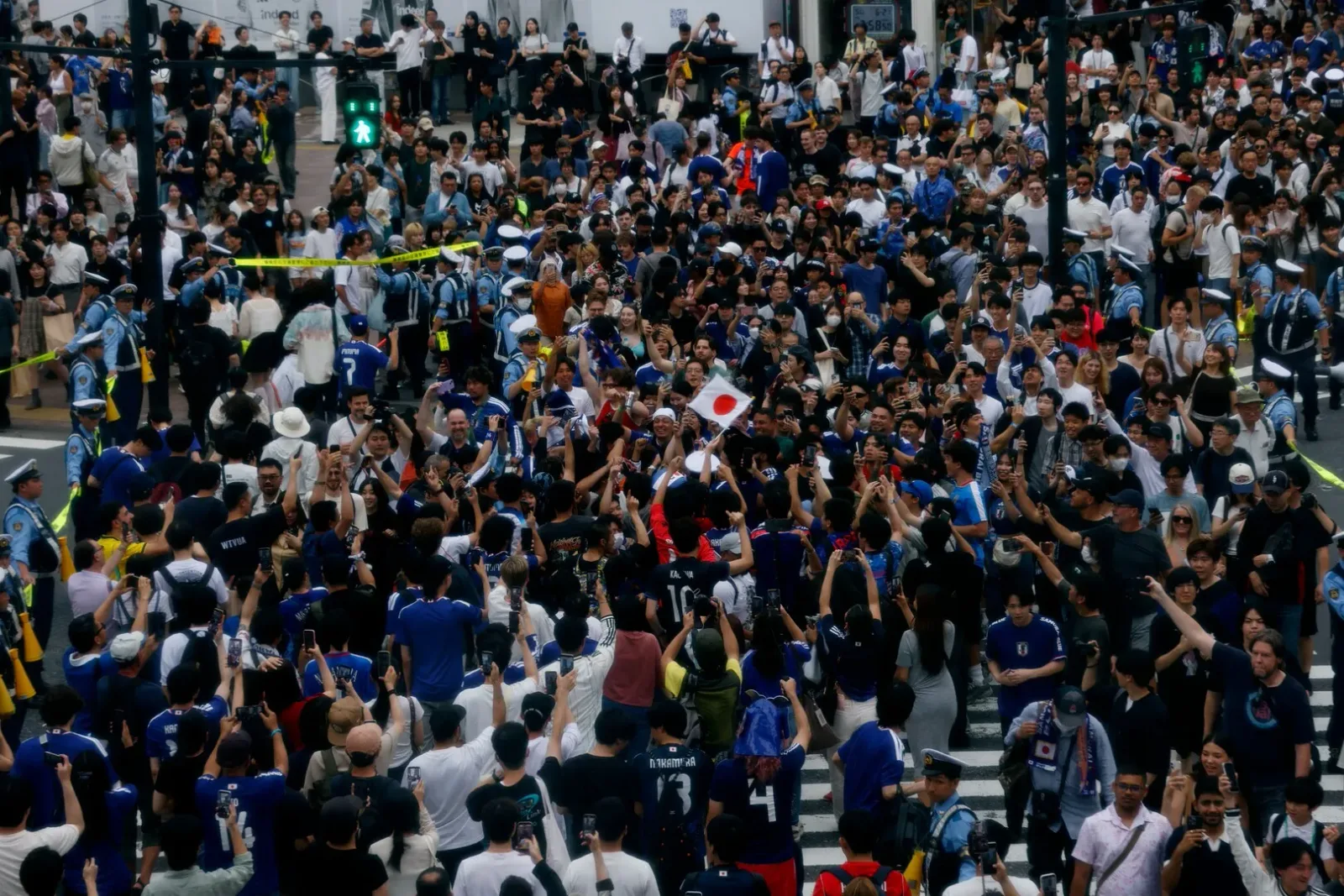 Suporteri japonezi sărbătoresc victoria la Shibuya Crossing, plini de entuziasm.
