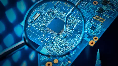 Detaliu al unui circuit integrat sub lupă, evidențiind complexitatea tehnologiei.