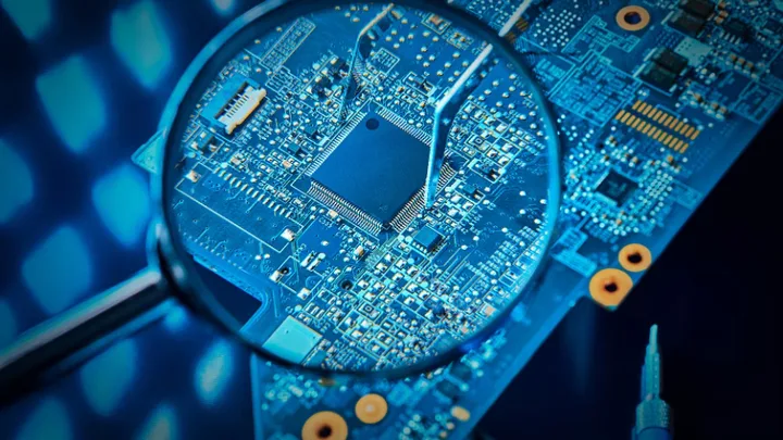 Detaliu al unui circuit integrat sub lupă, evidențiind complexitatea tehnologiei.