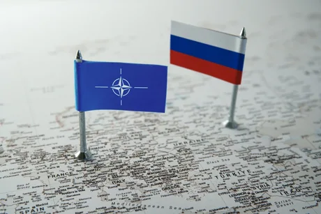 Steagurile NATO și Rusiei pe o hartă a Europei, simbolizând tensiuni geopolitice.