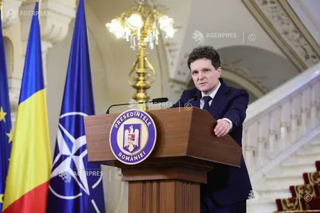 Nicușor Dan la o conferință de presă, cu steaguri în fundal.