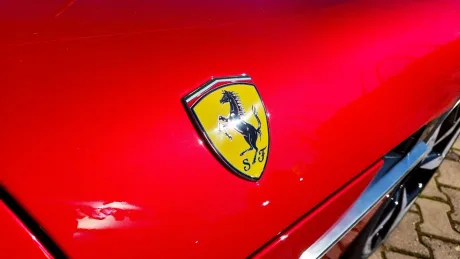 Sigla Ferrari pe un automobil roșu strălucitor, evidențiind designul iconic.
