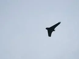 Un aparat de zbor neidentificat în aer, pe un fundal gri.