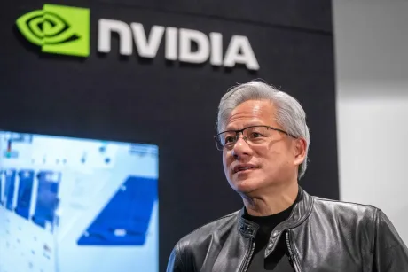 Jensen Huang discută despre strategia Nvidia la birou, cu logo-ul companiei în fundal.