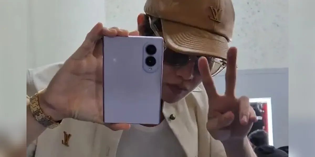 Un tânăr își face un selfie cu un telefon pliabil în mână.