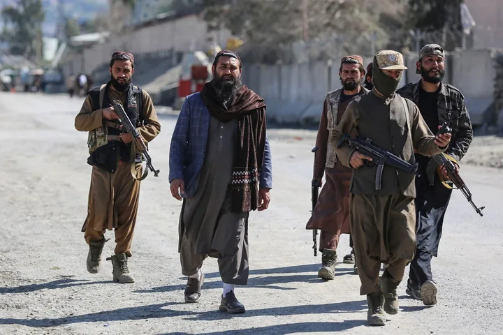 Membri ai talibanilor patrulează pe străzile din Afganistan, purtând arme.