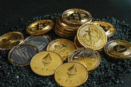 Monede cripto diverse, inclusiv Bitcoin și Ethereum, pe un fundal întunecat.