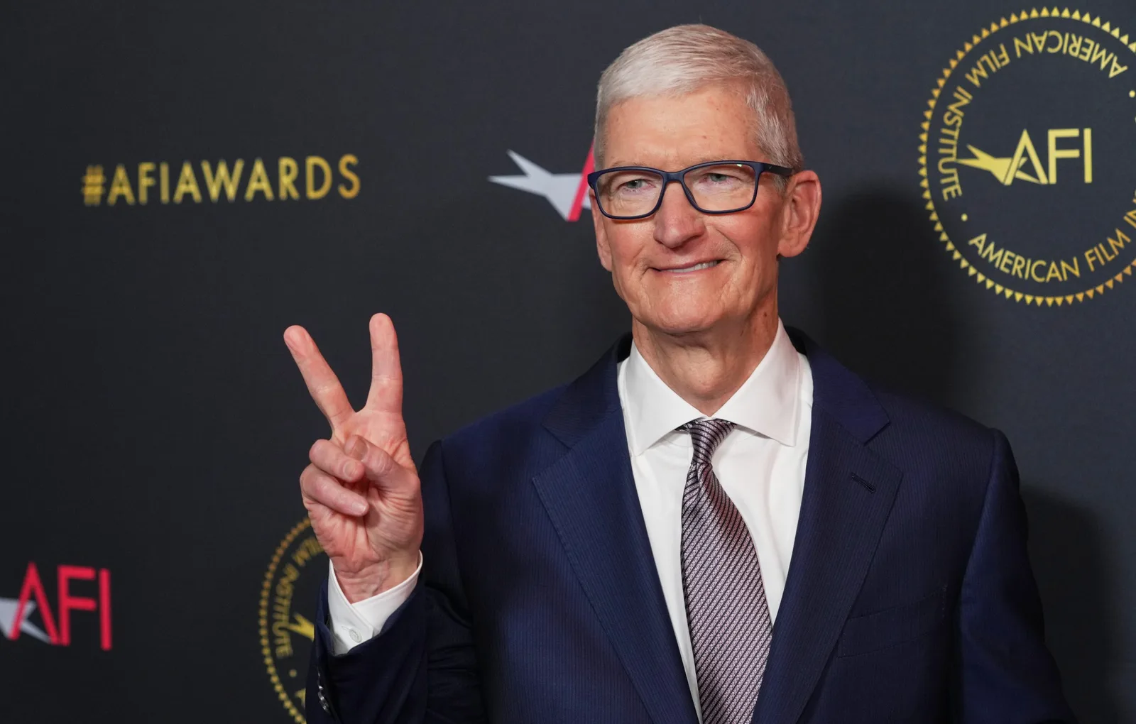 Directorul Apple la un eveniment important, zâmbind și făcând semnul păcii.