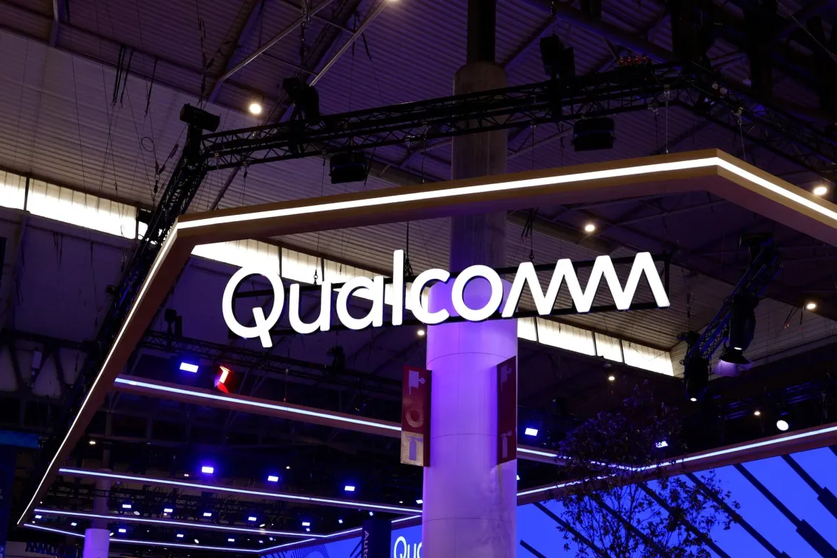 Logo-ul Qualcomm expus la un eveniment tehnologic, iluminat în nuanțe de albastru.