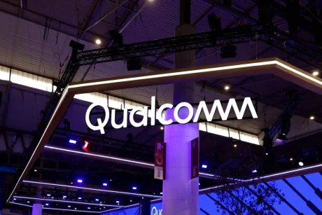 Logo-ul Qualcomm expus la un eveniment tehnologic, iluminat în nuanțe de albastru.