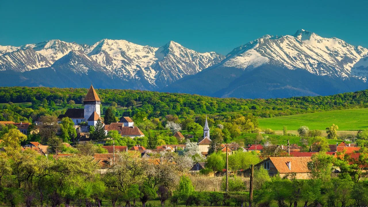 Peisaj montan în Munții Făgăraș, cu sate pitorești și vârfuri acoperite de zăpadă.