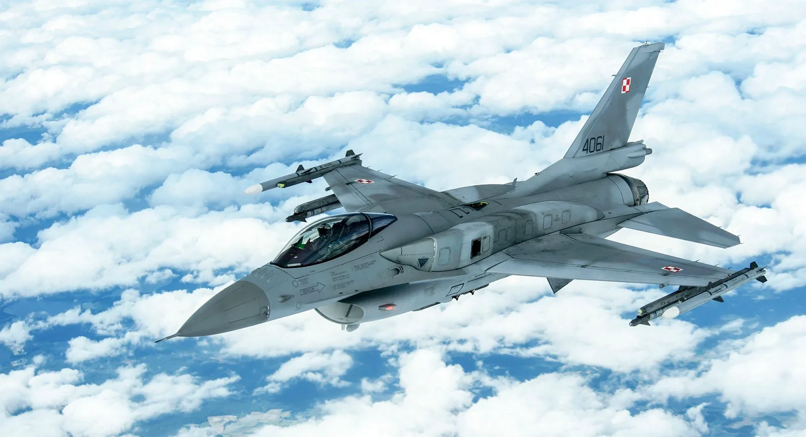 Avion de luptă F-16 polonez zburând deasupra norilor.