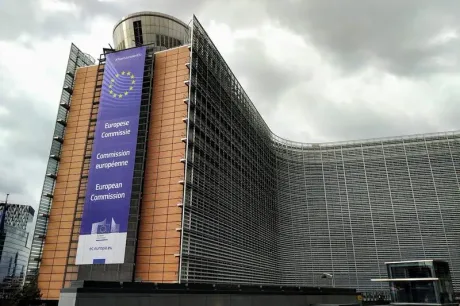 Clădirea Comisiei Europene cu un banner informativ pe fațadă.