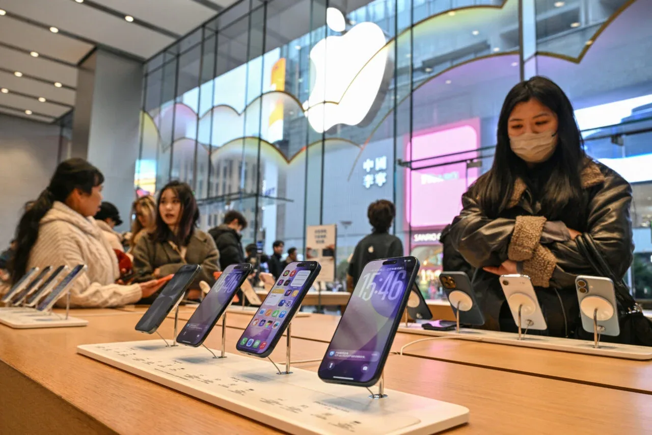 Clienți admirând smartphone-uri într-un magazin Apple.