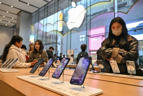 Clienți admirând smartphone-uri într-un magazin Apple.