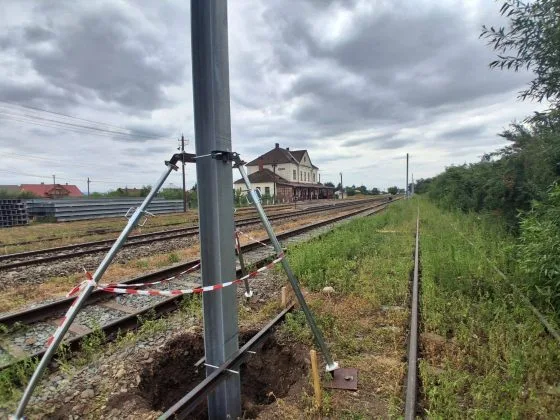 Lucrări de electrificare pe linia ferată Dărmănești–Vicșani, cu stâlpi metalici montați.
