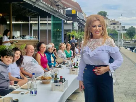 Oameni relaxându-se la o masă pe litoralul românesc, bucurându-se de vremea frumoasă.