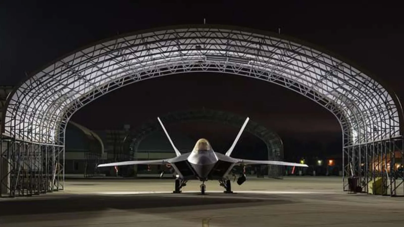 Avion militar F-22 Raptor expus sub un adăpost nocturn.