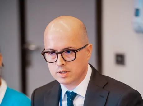 Un bărbat cu ochelari discută despre impactul inteligenței artificiale în România.