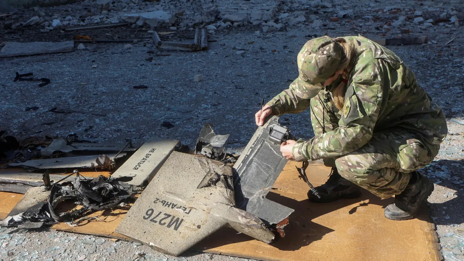 Soldat inspectând resturi ale unei drone distruse.