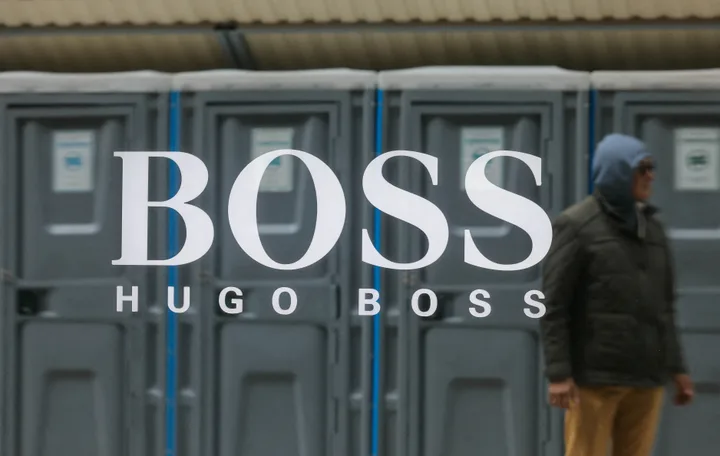 Logo-ul Hugo Boss pe fundal urban, cu un bărbat în apropiere.