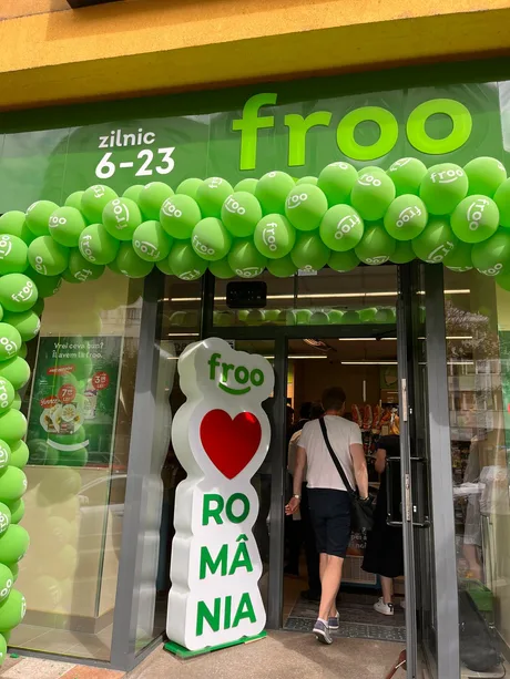 Intrarea unui magazin Froo, decorat cu baloane verzi, în România.