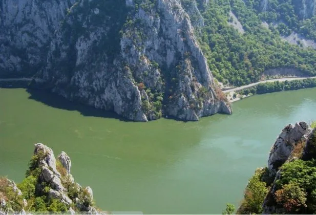 Peisaj montan cu apă verde și stânci în jurul lacului de acumulare.