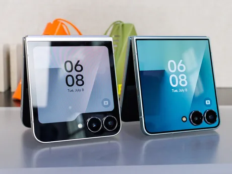 Două telefoane pliabile Galaxy Z Flip8 expuse pe o masă, cu ecrane colorate.