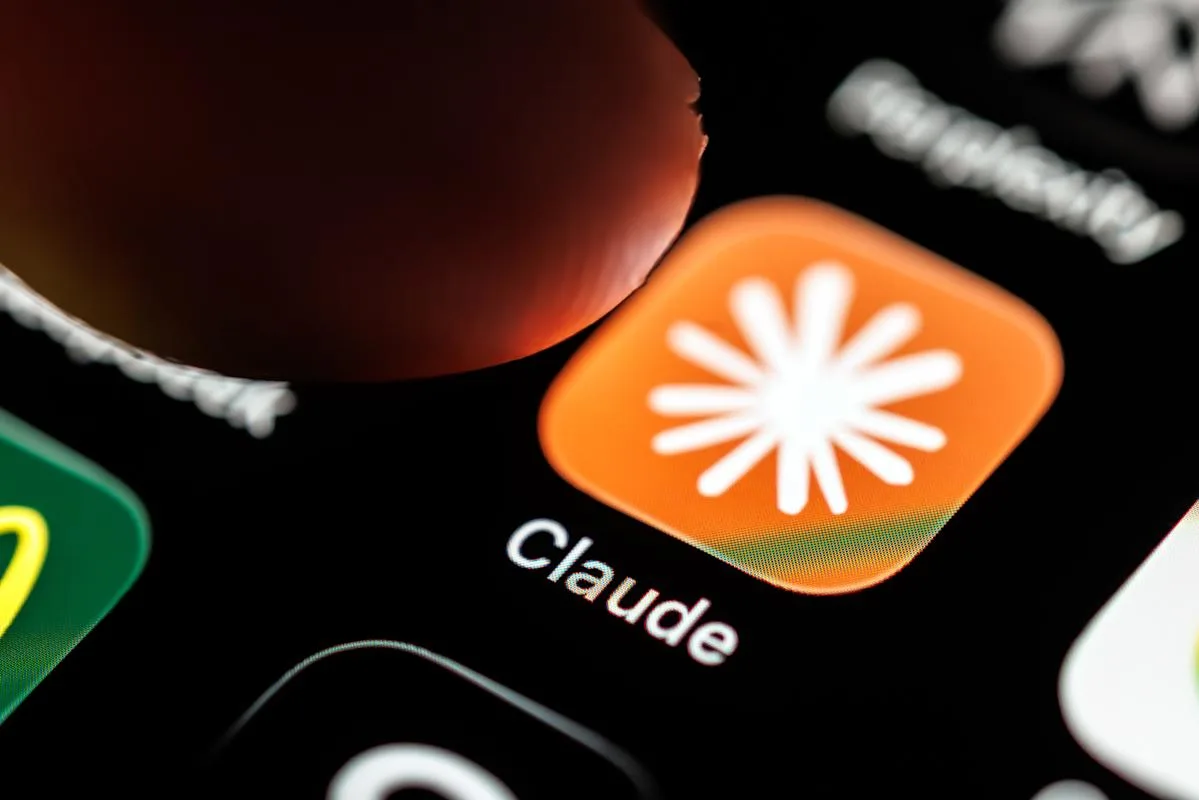 Aplicația Claude pe un ecran de telefon mobil, cu un deget indicând-o.