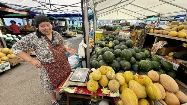 Vânzătoare la piață, înconjurată de pepeni de Dăbuleni proaspeți.