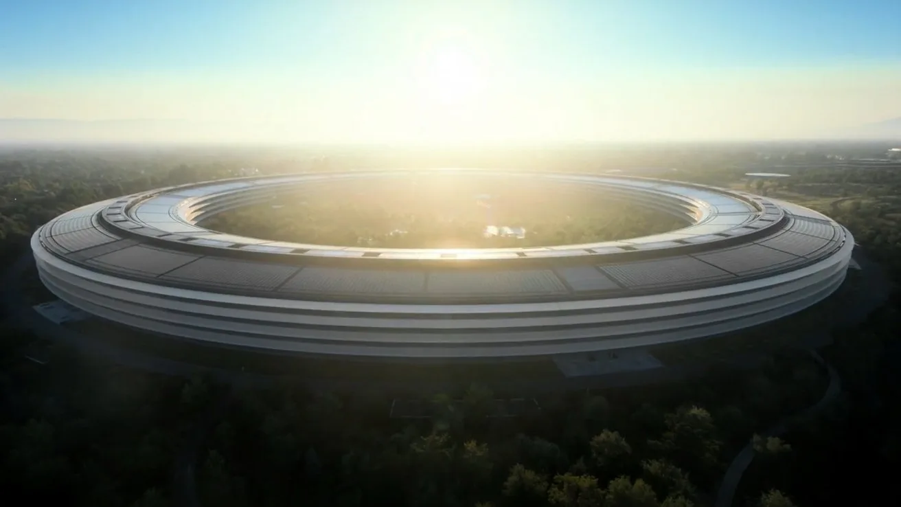 Vedere panoramică a sediului Apple în lumina dimineții, cu soarele răsărind în fundal.