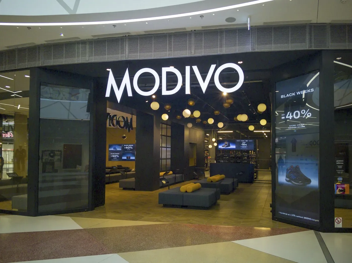 Intrarea unui magazin Modivo, cu decor modern și iluminare caldă.
