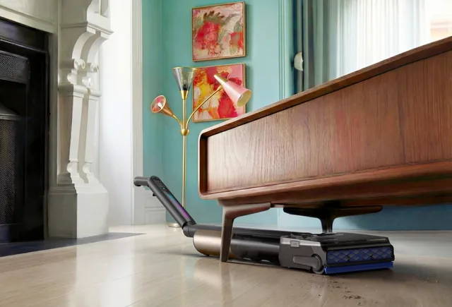 Aspirator Tineco curățând sub un mobilier joasă într-un interior colorat.
